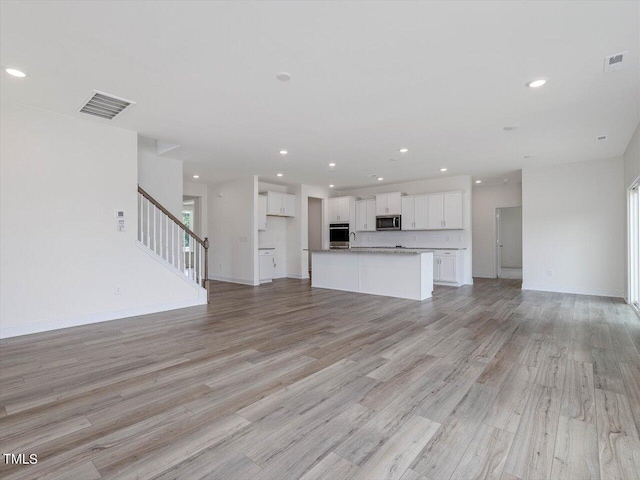 unfurnished living room with stairway, visible vents, and recessed lighting