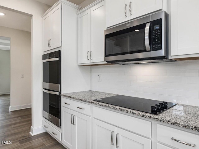 kitchen with light stone counters, white cabinets, appliances with stainless steel finishes, backsplash, and dark wood finished floors