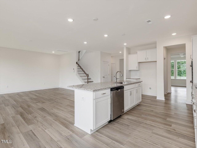 kitchen featuring visible vents, white cabinets, dishwasher, light wood-style floors, and a sink