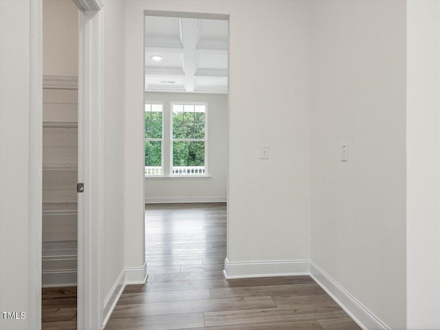 corridor with baseboards, coffered ceiling, dark wood-type flooring, and beamed ceiling