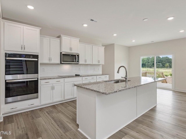 kitchen featuring stainless steel appliances, backsplash, a sink, and white cabinets