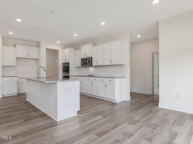 kitchen featuring white cabinetry, light wood finished floors, tasteful backsplash, and appliances with stainless steel finishes