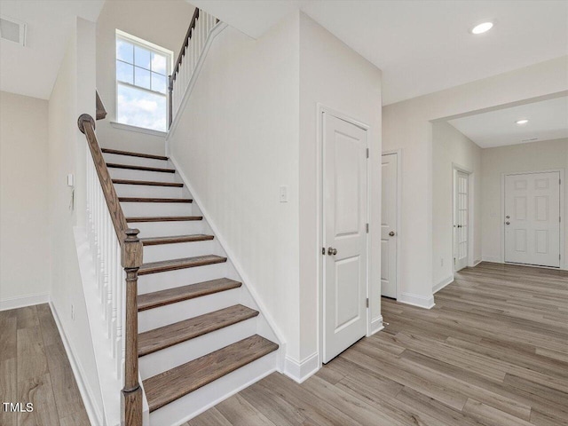 staircase with recessed lighting, wood finished floors, visible vents, and baseboards