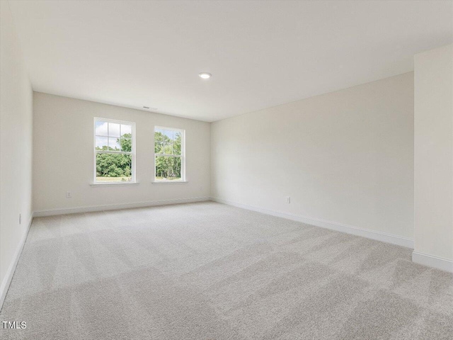 empty room featuring light colored carpet and baseboards