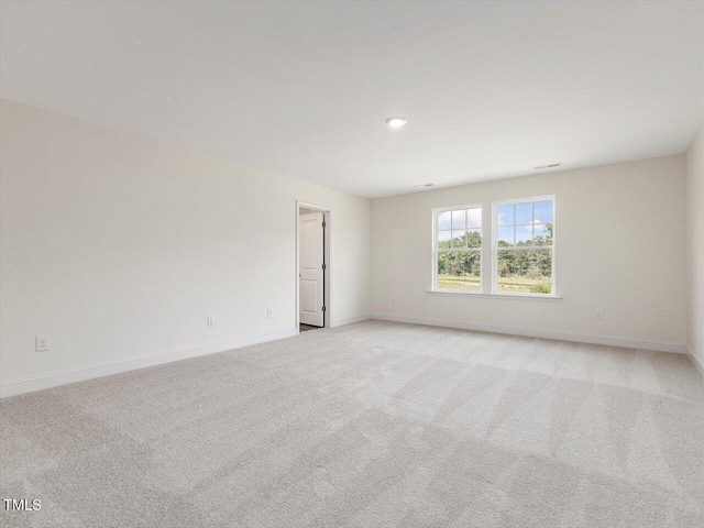 unfurnished room with light colored carpet and baseboards