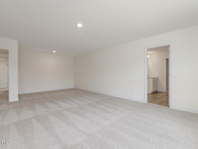 empty room featuring recessed lighting, light colored carpet, and baseboards