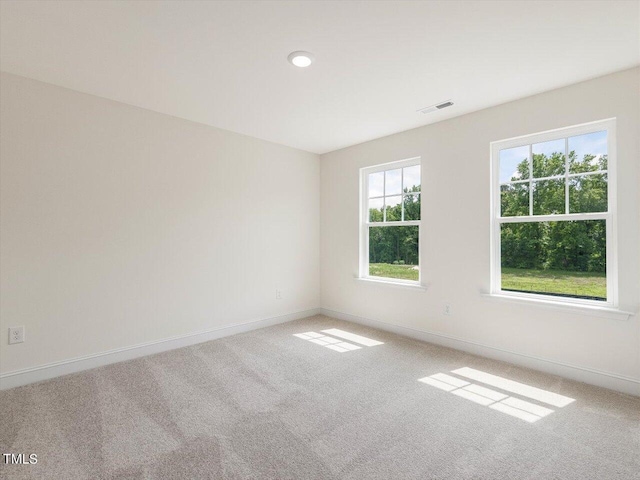 unfurnished room with carpet floors, visible vents, and baseboards