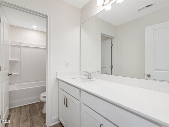 bathroom featuring toilet, wood finished floors, vanity, and visible vents