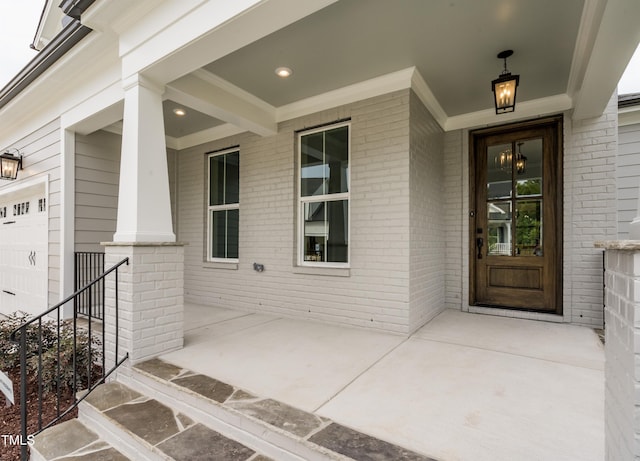 view of exterior entry with covered porch and brick siding