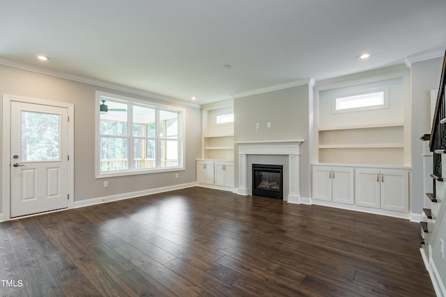 unfurnished living room with baseboards, dark wood finished floors, crown molding, built in shelves, and a fireplace