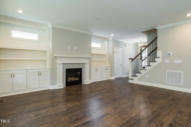 unfurnished living room featuring built in features, dark wood finished floors, visible vents, a tile fireplace, and stairs