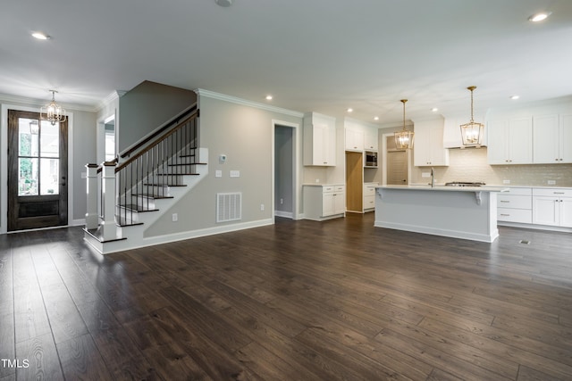 unfurnished living room featuring a chandelier, dark wood-style flooring, visible vents, stairs, and ornamental molding