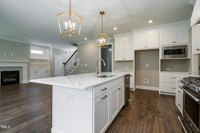 kitchen featuring a tile fireplace, dark wood-style flooring, a sink, open floor plan, and appliances with stainless steel finishes