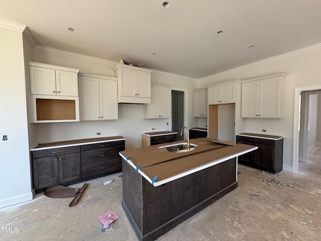 kitchen featuring ornamental molding, a sink, and a center island with sink