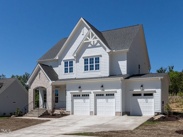 craftsman-style house with an attached garage, a shingled roof, and driveway