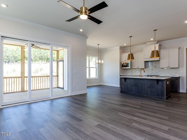 kitchen featuring open floor plan, recessed lighting, stainless steel microwave, tasteful backsplash, and ceiling fan with notable chandelier