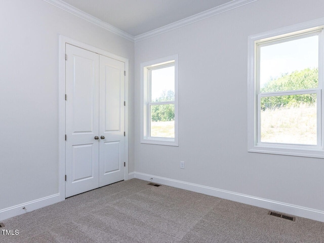unfurnished bedroom featuring crown molding, baseboards, carpet, and visible vents