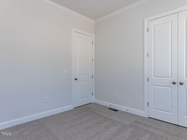 unfurnished room featuring carpet floors, baseboards, visible vents, and ornamental molding