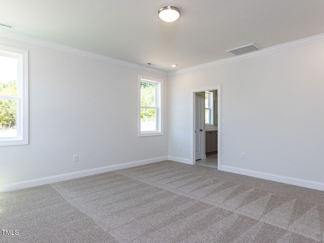 carpeted spare room with crown molding, baseboards, and visible vents