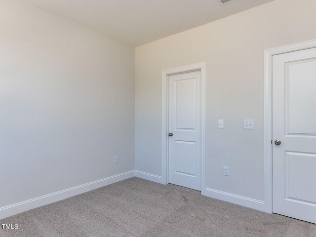 empty room featuring baseboards, visible vents, and light carpet