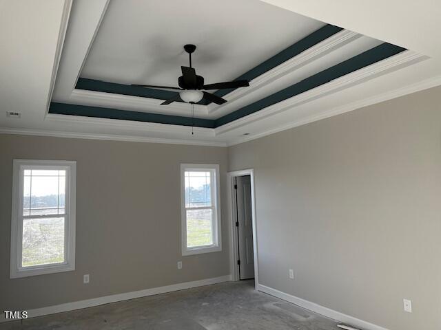 empty room featuring baseboards, ornamental molding, and a raised ceiling