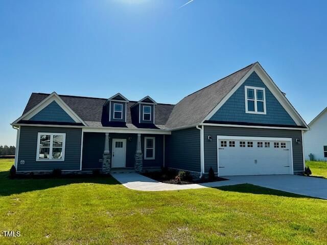 craftsman inspired home with driveway, an attached garage, and a front lawn