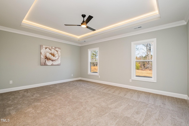 carpeted spare room featuring a tray ceiling, ceiling fan, and ornamental molding