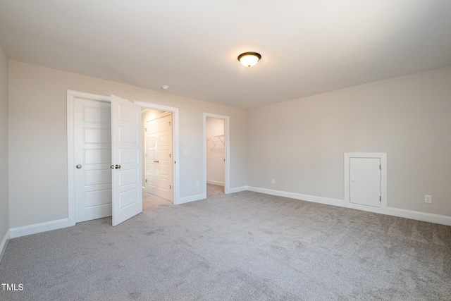 unfurnished bedroom with a walk in closet, light colored carpet, and a closet