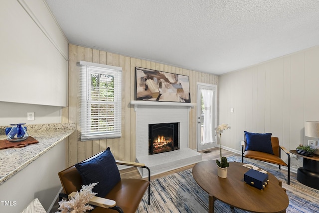 603 E Park St, Cary, NC 27511 - living area featuring a fireplace, a textured ceiling, wood finished floors, and wood walls