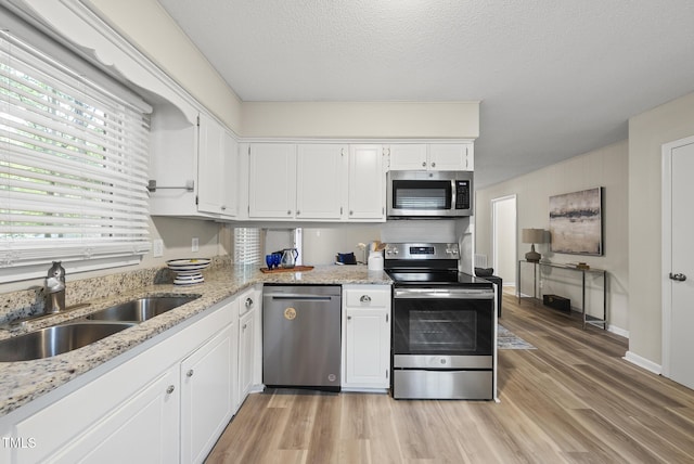 603 E Park St, Cary, NC 27511 - kitchen featuring appliances with stainless steel finishes, light wood-style flooring, white cabinets, and light stone counters