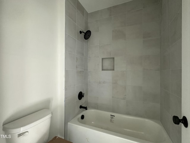 bathroom featuring tiled shower / bath combo and toilet