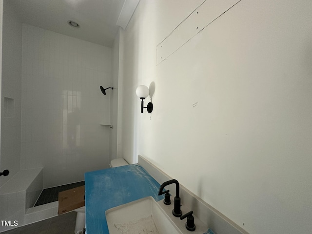 bathroom featuring tiled shower, sink, and tile patterned floors