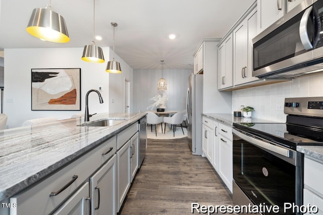 kitchen featuring hanging light fixtures, appliances with stainless steel finishes, sink, and dark wood-type flooring