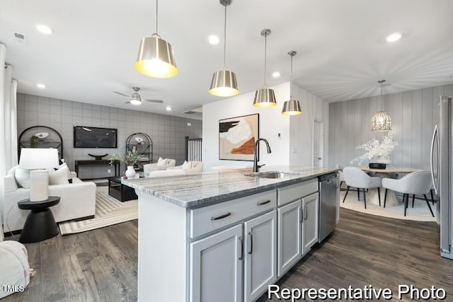 kitchen featuring light stone counters, stainless steel appliances, decorative light fixtures, and sink