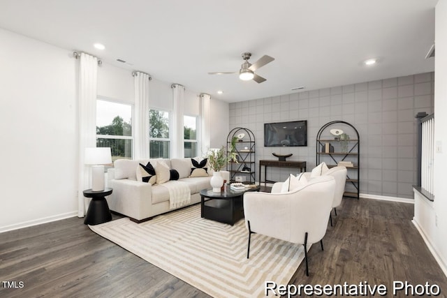 living room with ceiling fan, dark hardwood / wood-style flooring, and tile walls