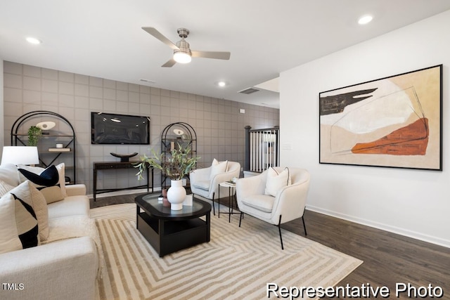 living room featuring ceiling fan, hardwood / wood-style floors, and tile walls