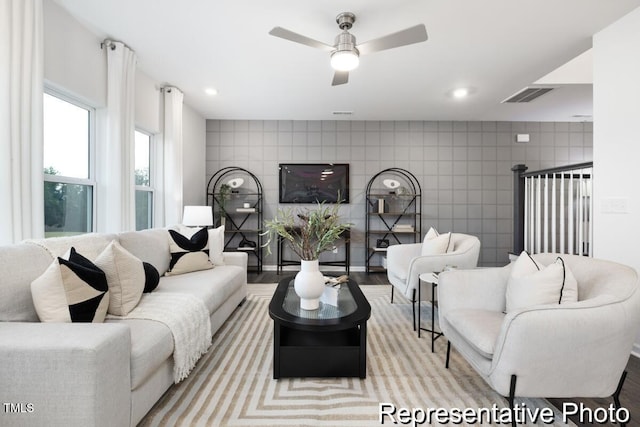 living room with tile walls, light hardwood / wood-style floors, and ceiling fan