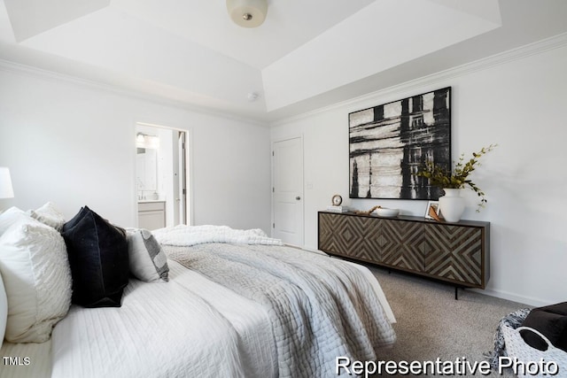 carpeted bedroom with crown molding, a raised ceiling, and ensuite bathroom