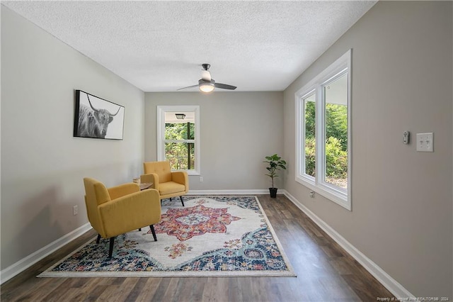 sitting room with ceiling fan, plenty of natural light, and dark hardwood / wood-style flooring