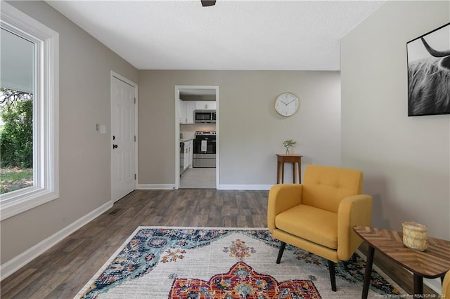 sitting room with plenty of natural light and dark wood-type flooring