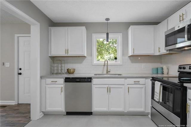 kitchen featuring white cabinets, pendant lighting, sink, appliances with stainless steel finishes, and decorative backsplash