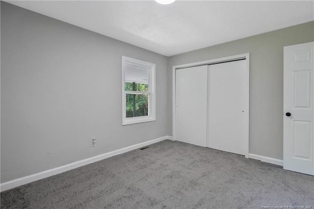 unfurnished bedroom featuring light carpet, a closet, and a textured ceiling