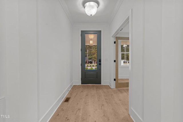 doorway to outside featuring light wood-type flooring, baseboards, visible vents, and ornamental molding