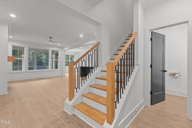 staircase with hardwood / wood-style flooring and ceiling fan with notable chandelier