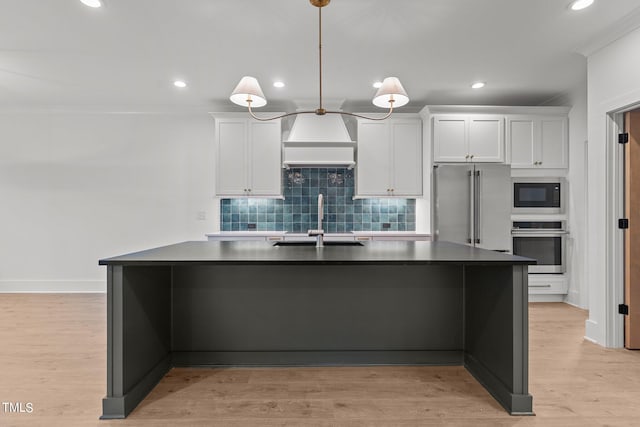 kitchen featuring white cabinets, premium range hood, hanging light fixtures, light hardwood / wood-style flooring, and appliances with stainless steel finishes