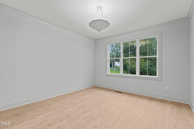 unfurnished room featuring crown molding, visible vents, light wood-style flooring, and baseboards