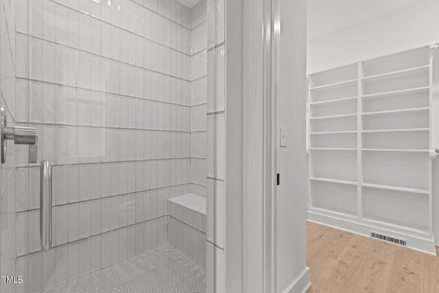 bathroom featuring wood finished floors, visible vents, and a shower stall