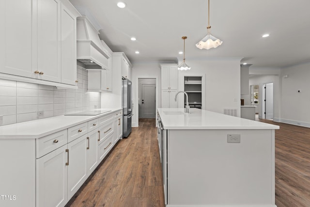 kitchen featuring black electric stovetop, a sink, visible vents, custom exhaust hood, and freestanding refrigerator