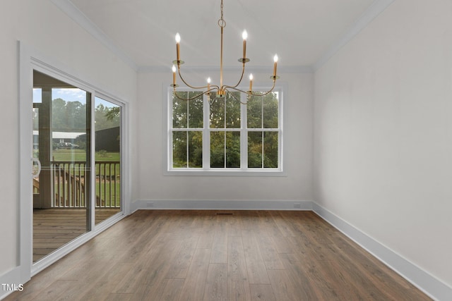 unfurnished dining area featuring a healthy amount of sunlight, ornamental molding, an inviting chandelier, and hardwood / wood-style flooring