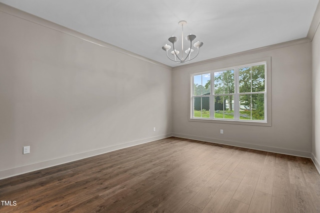 unfurnished room with a notable chandelier, dark wood-type flooring, and crown molding